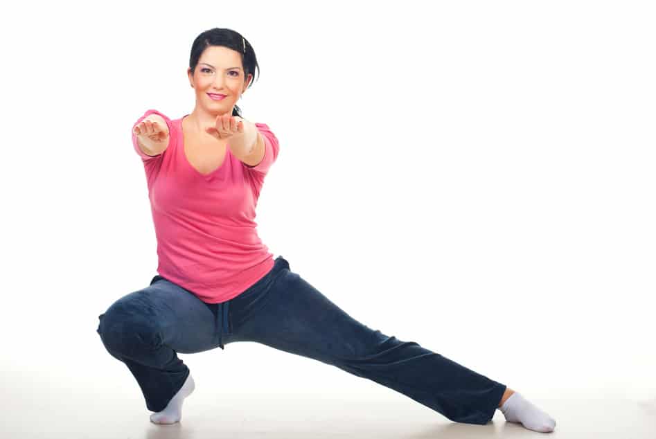 Woman doing lateral lunge and standing with hands outstretched on floor over white background